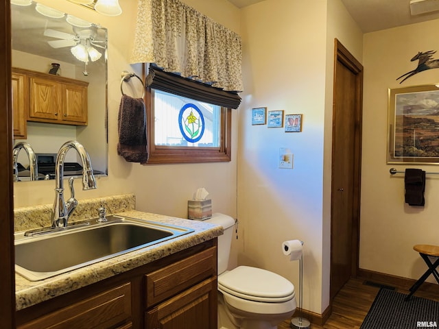 bathroom with ceiling fan, vanity, wood-type flooring, and toilet