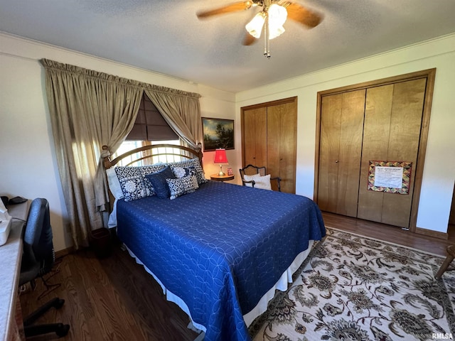 bedroom featuring ceiling fan, dark hardwood / wood-style floors, a textured ceiling, and two closets