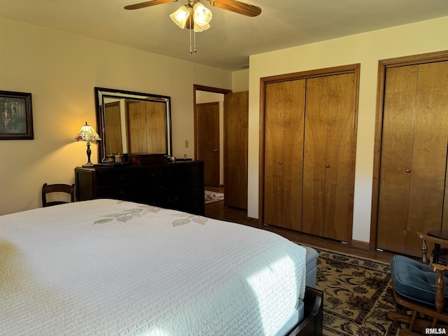 bedroom with two closets, ceiling fan, and dark hardwood / wood-style floors