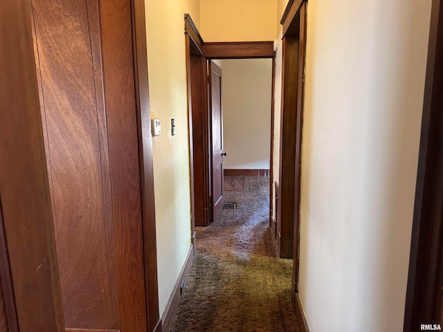 hall featuring dark colored carpet