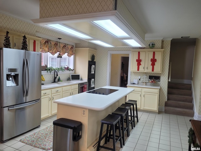 kitchen featuring cream cabinetry, appliances with stainless steel finishes, hanging light fixtures, and sink