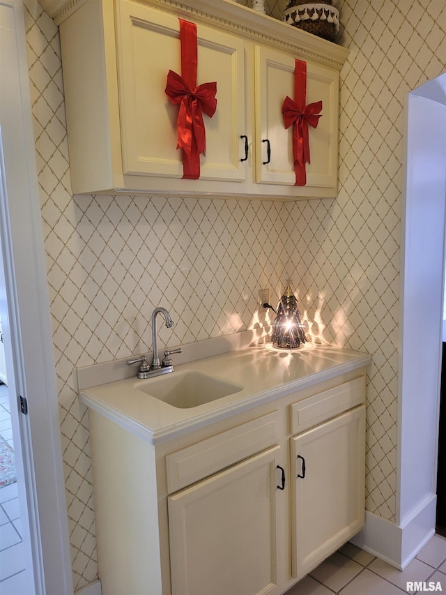 kitchen featuring decorative backsplash, sink, light tile patterned floors, and cream cabinetry