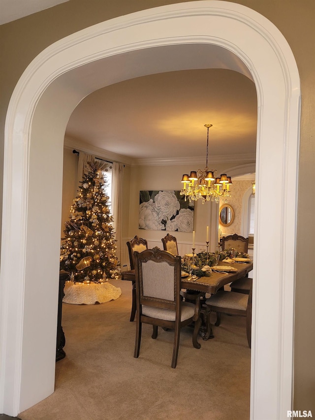 dining space with a chandelier, carpet flooring, and crown molding