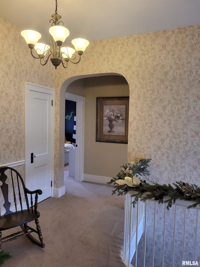 corridor with carpet and an inviting chandelier