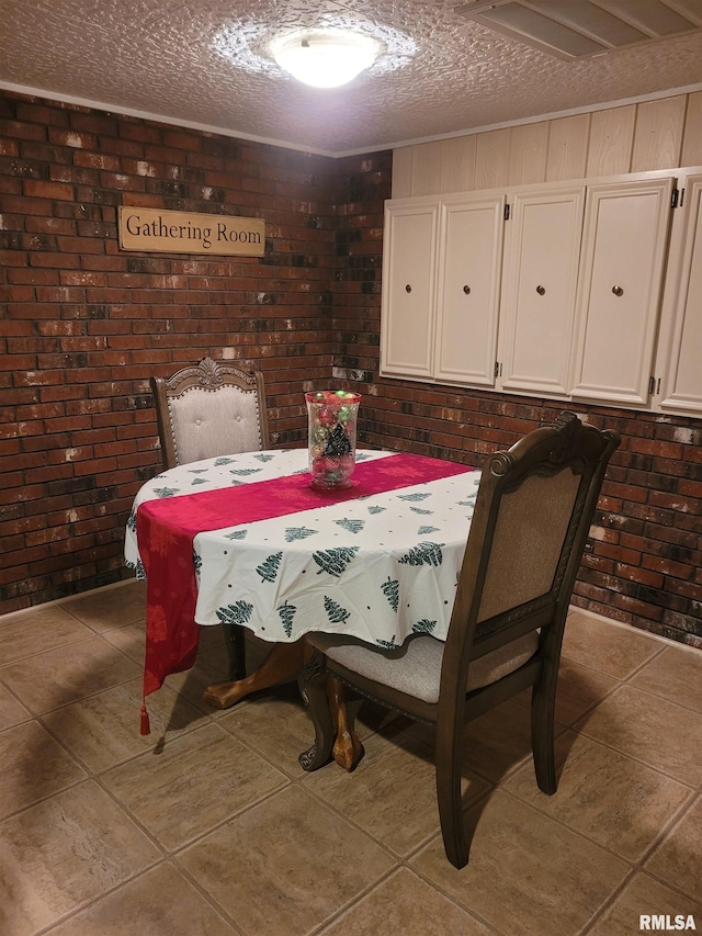 dining room with dark tile patterned flooring, a textured ceiling, and brick wall