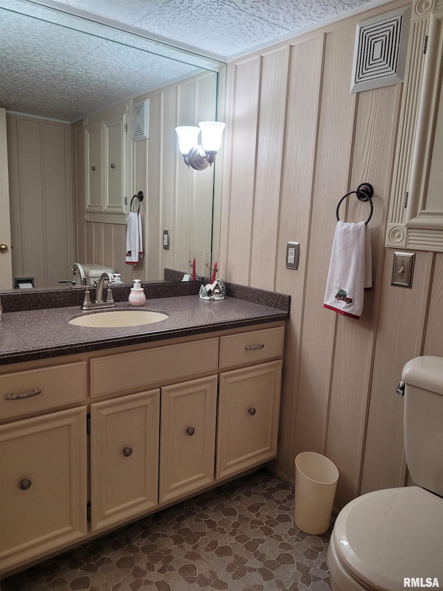 bathroom with vanity, toilet, and a textured ceiling