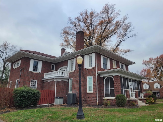 view of side of home with a lawn, a sunroom, a balcony, and cooling unit