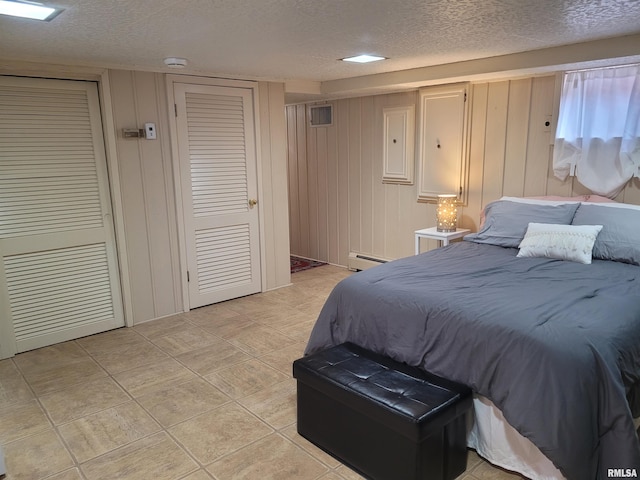 bedroom with a textured ceiling and a baseboard heating unit