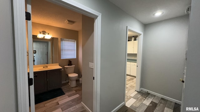 bathroom featuring hardwood / wood-style floors, vanity, toilet, and a textured ceiling