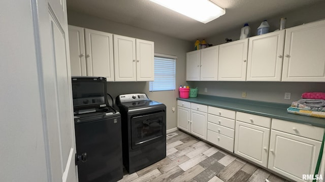 clothes washing area featuring washer and dryer, light hardwood / wood-style floors, and cabinets