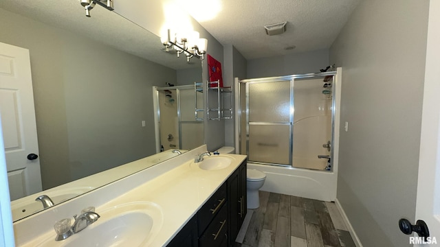 full bathroom with vanity, a textured ceiling, wood-type flooring, enclosed tub / shower combo, and toilet