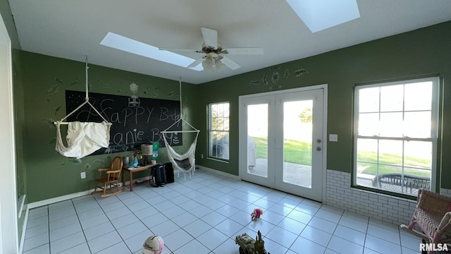 doorway featuring light tile patterned flooring, a skylight, a wealth of natural light, and ceiling fan