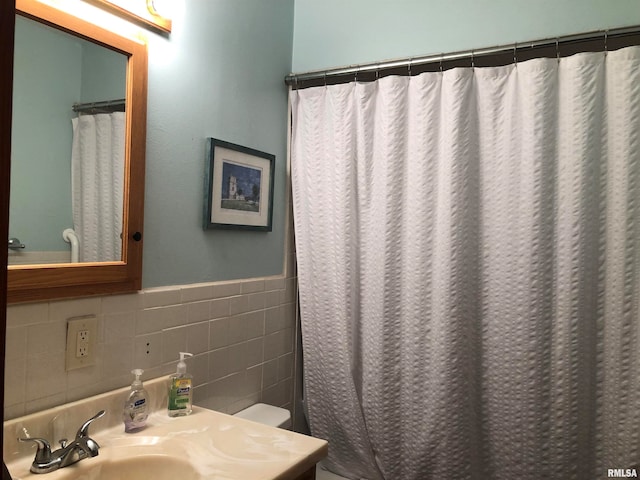 bathroom with a shower with curtain, sink, tile walls, and toilet