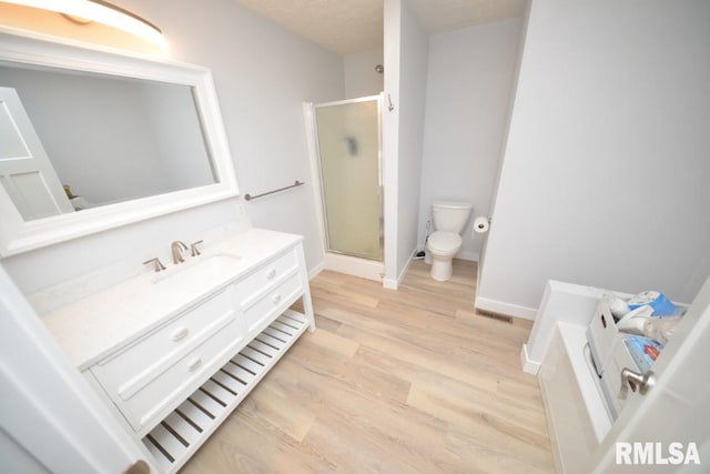 bathroom featuring walk in shower, hardwood / wood-style floors, a textured ceiling, toilet, and vanity