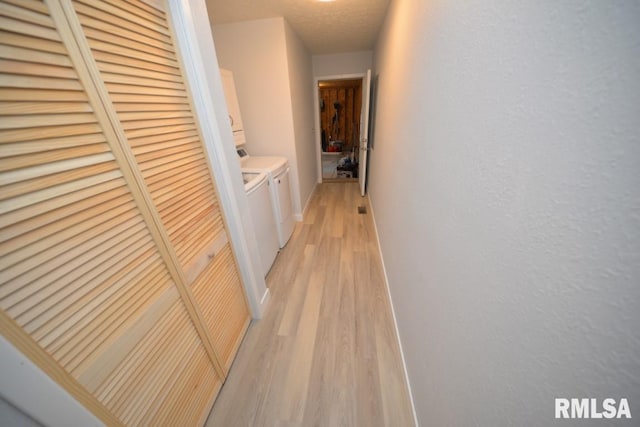 hall featuring separate washer and dryer, light hardwood / wood-style flooring, and a textured ceiling