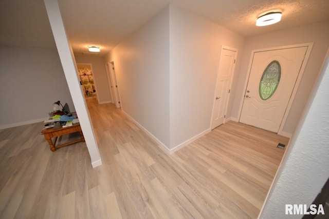 entryway with a textured ceiling and light hardwood / wood-style flooring