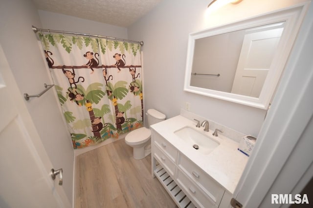 bathroom with hardwood / wood-style floors, vanity, a shower with shower curtain, toilet, and a textured ceiling