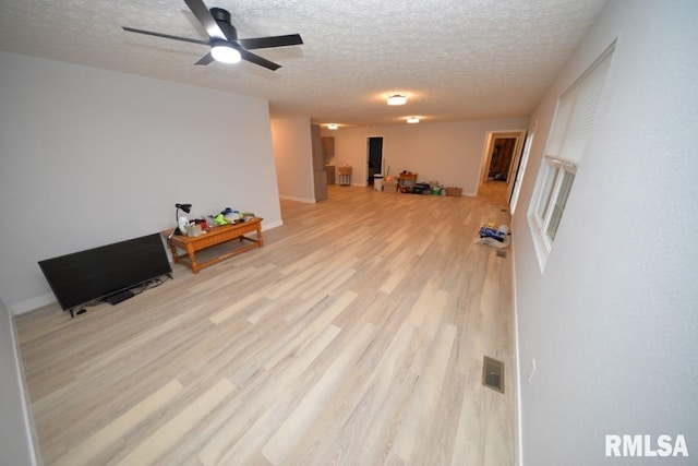 interior space with a textured ceiling, light wood-type flooring, and ceiling fan