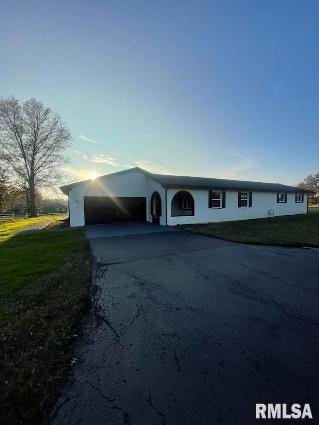 ranch-style home featuring a garage and a front lawn