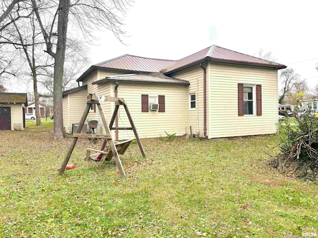 rear view of property featuring a lawn and cooling unit