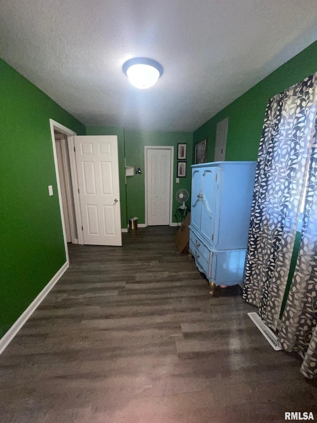 laundry room with dark hardwood / wood-style flooring, stacked washing maching and dryer, and a textured ceiling