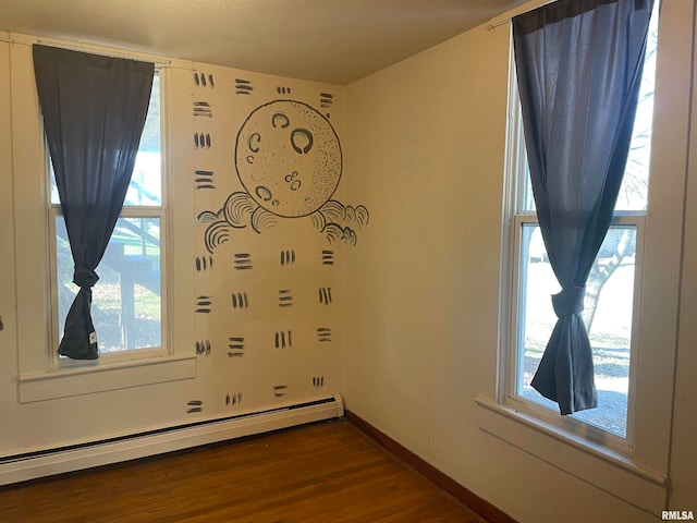 unfurnished room featuring baseboard heating, a healthy amount of sunlight, and hardwood / wood-style flooring