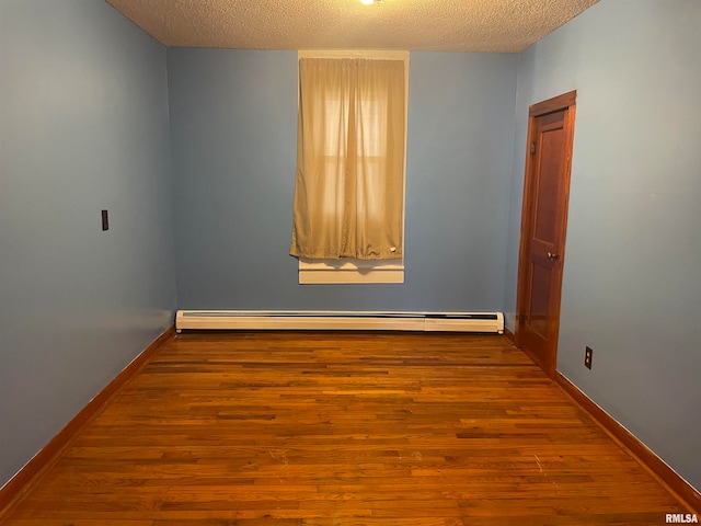 spare room featuring a baseboard radiator, a textured ceiling, and hardwood / wood-style flooring