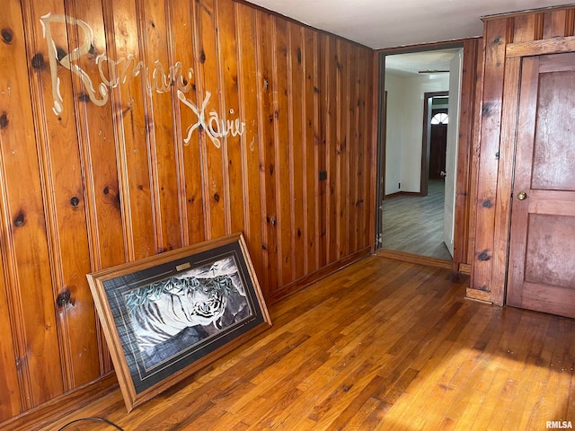 corridor with wood walls and wood-type flooring