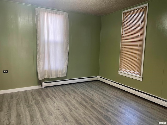 unfurnished room featuring baseboard heating, hardwood / wood-style floors, and a textured ceiling