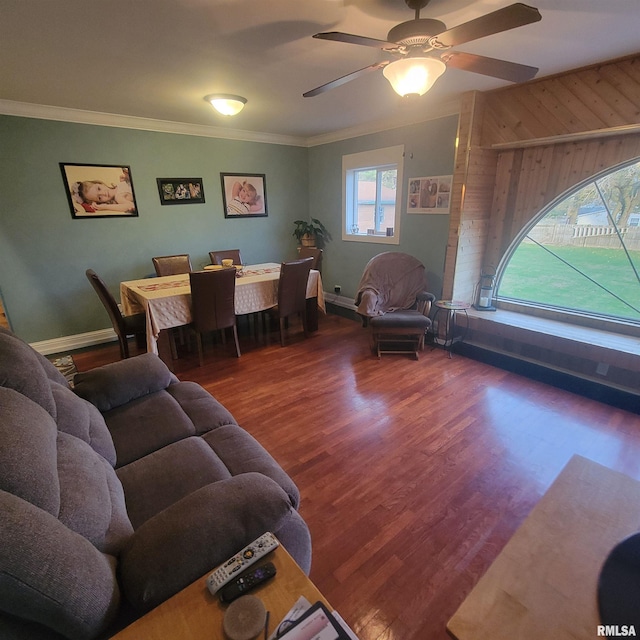 living room featuring hardwood / wood-style floors, wooden walls, ceiling fan, and ornamental molding