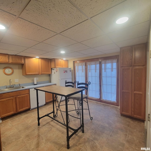 kitchen with a paneled ceiling, sink, and white appliances