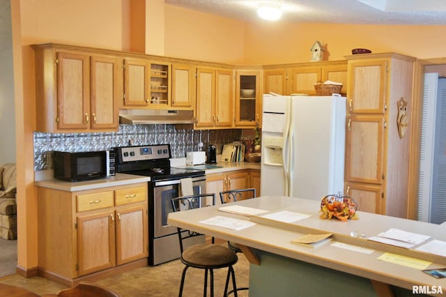 kitchen featuring lofted ceiling, white refrigerator with ice dispenser, stainless steel electric stove, tasteful backsplash, and a breakfast bar area