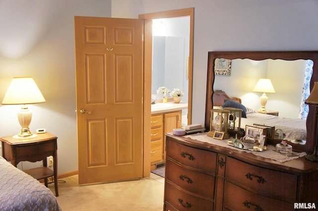 bedroom featuring ensuite bathroom, sink, and light colored carpet