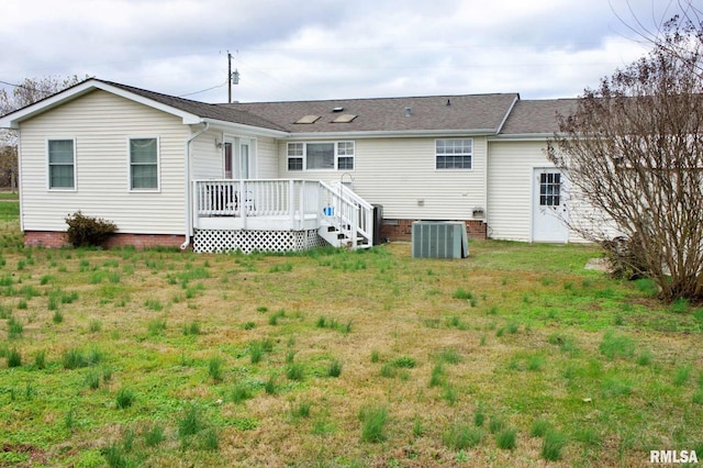 rear view of house featuring central air condition unit, a deck, and a lawn