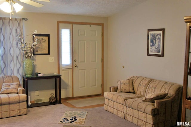 carpeted living room with ceiling fan and a textured ceiling