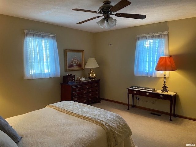 bedroom with multiple windows, ceiling fan, and light carpet