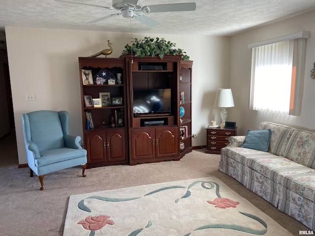 living room with ceiling fan, carpet floors, and a textured ceiling