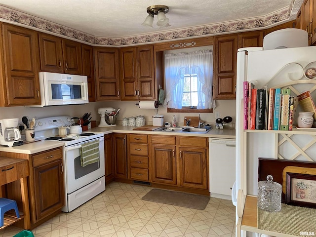 kitchen with a textured ceiling, sink, light tile patterned floors, and white appliances