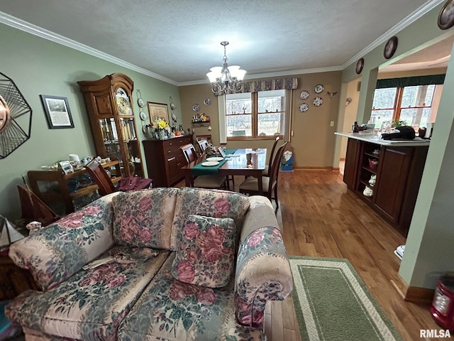 dining room featuring light hardwood / wood-style flooring, a wealth of natural light, ornamental molding, and a notable chandelier