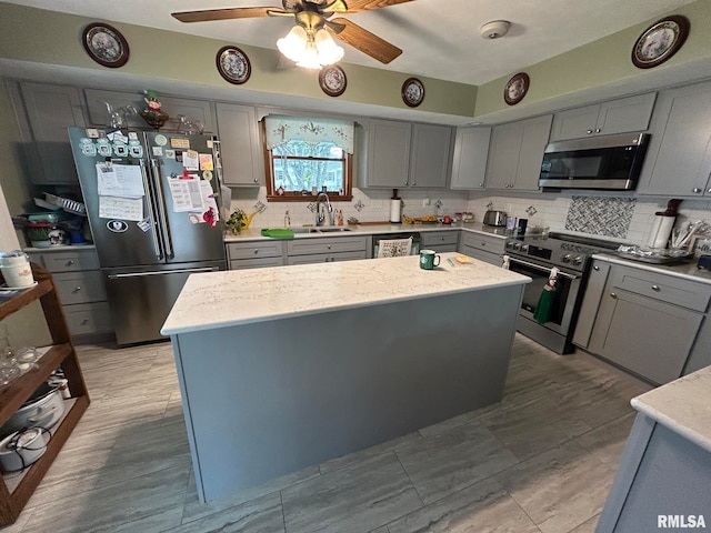 kitchen featuring gray cabinetry, sink, tasteful backsplash, a kitchen island, and stainless steel appliances