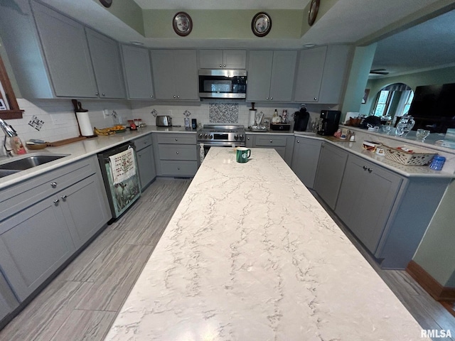 kitchen with backsplash, stainless steel appliances, gray cabinetry, and sink