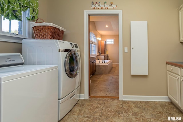 laundry room featuring separate washer and dryer, light tile patterned floors, and cabinets