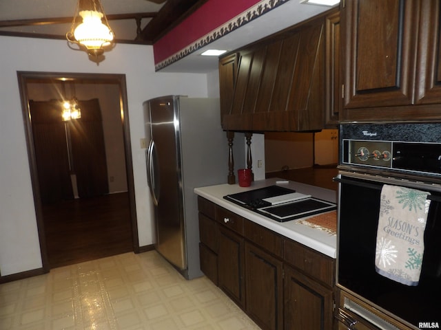 kitchen featuring oven, decorative light fixtures, dark brown cabinets, cooktop, and stainless steel refrigerator