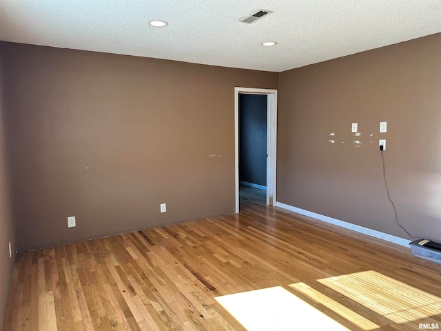 unfurnished room with a textured ceiling and hardwood / wood-style flooring