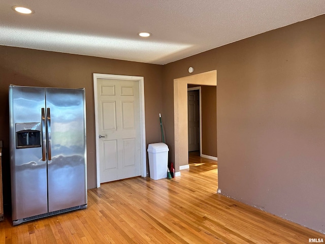 interior space featuring stainless steel fridge, a textured ceiling, and light hardwood / wood-style flooring