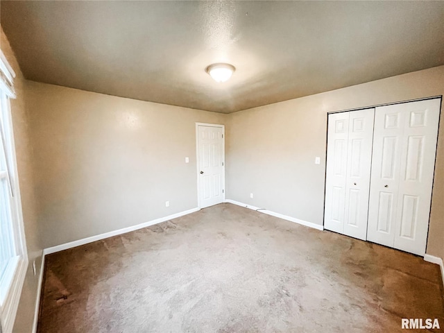 unfurnished bedroom with dark colored carpet and a closet