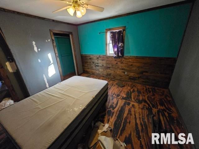 bedroom featuring wood-type flooring, ceiling fan, crown molding, and wood walls