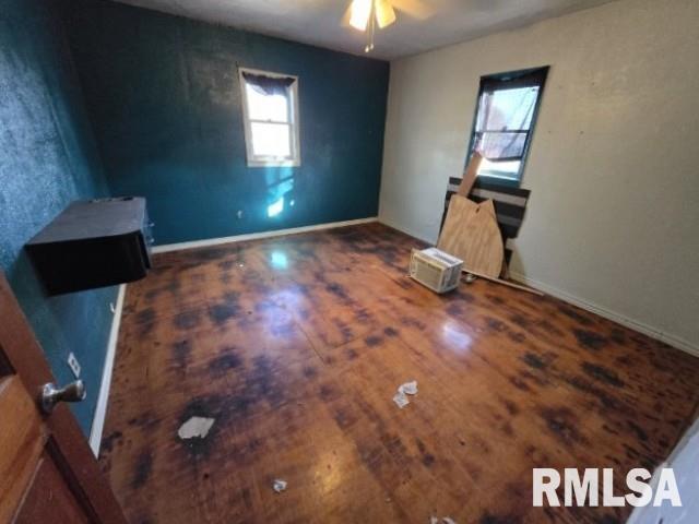 empty room with dark hardwood / wood-style flooring, ceiling fan, and plenty of natural light