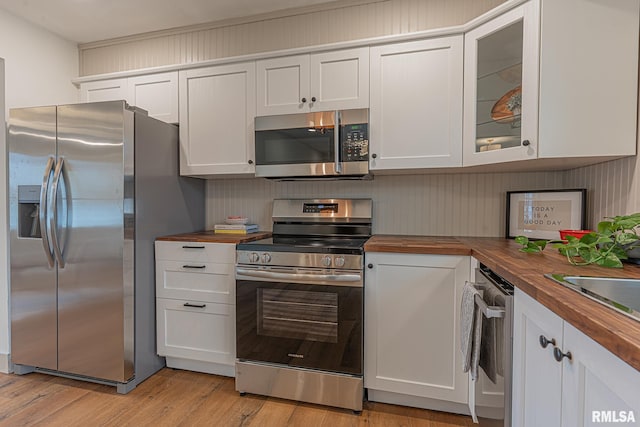 kitchen with light wood-type flooring, butcher block countertops, white cabinetry, and stainless steel appliances