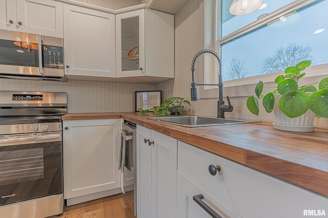 kitchen with sink, white cabinets, stainless steel appliances, and wood counters